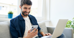 Man sitting on couch with laptop transferring money from one bank to another
